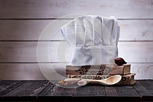 Cook hat, wooden spoons, spices and vegetables on a wooden table.ÃÂ 